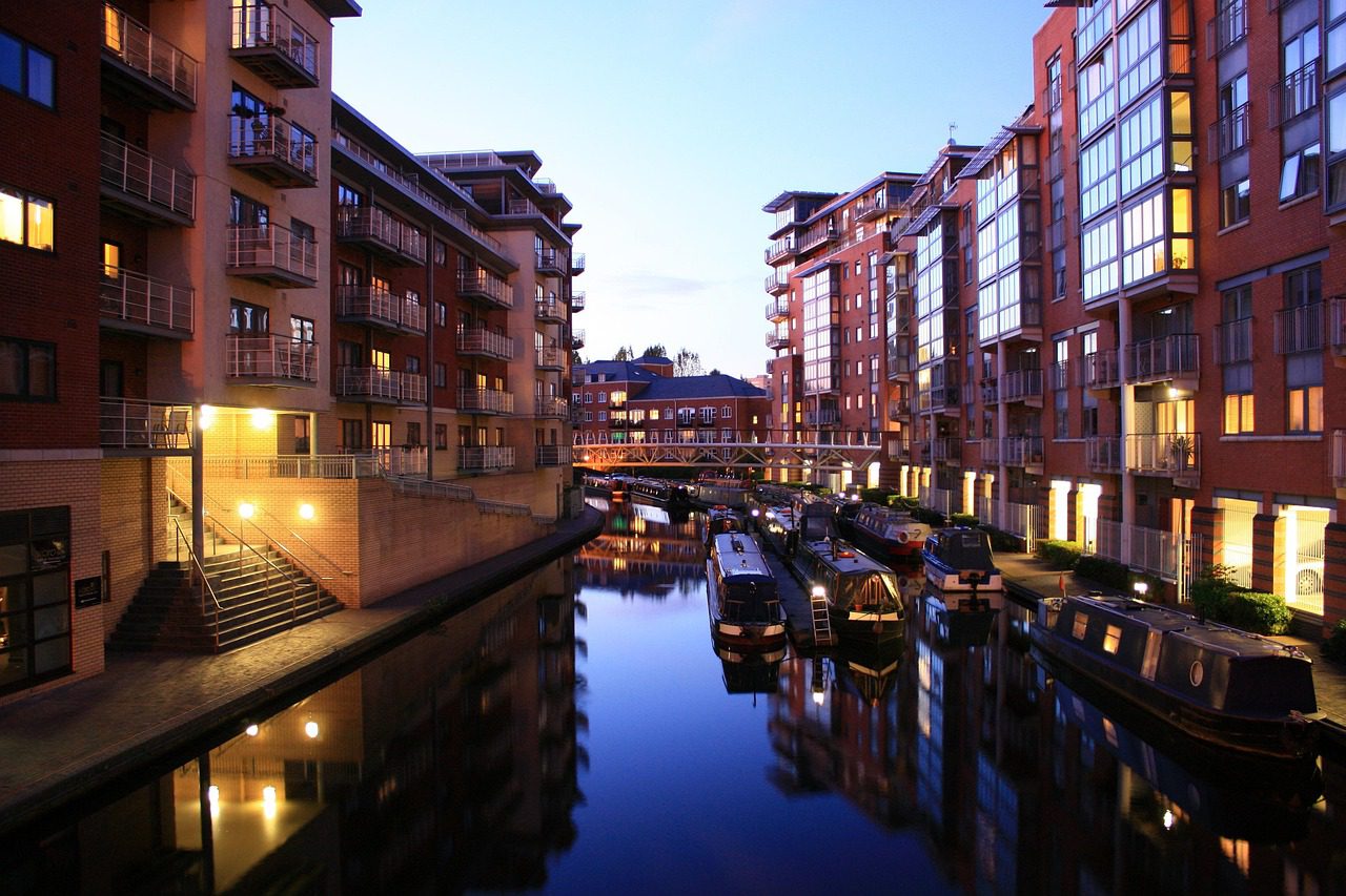 A canal in Birmingham, UK with boats and lights from buildings